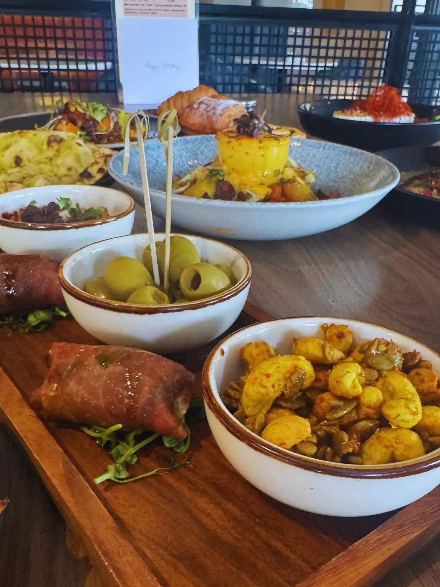 Brasserie Mezze Board at The Brasserie at Darleys, green olives, spiced cashews, prosciutto-wrapped parcels and dips in ceramic bowls on a wooden board